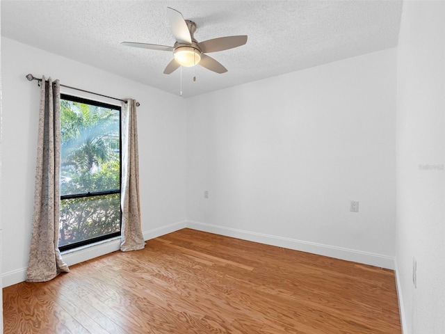 unfurnished room featuring ceiling fan, light wood-style floors, baseboards, and a textured ceiling