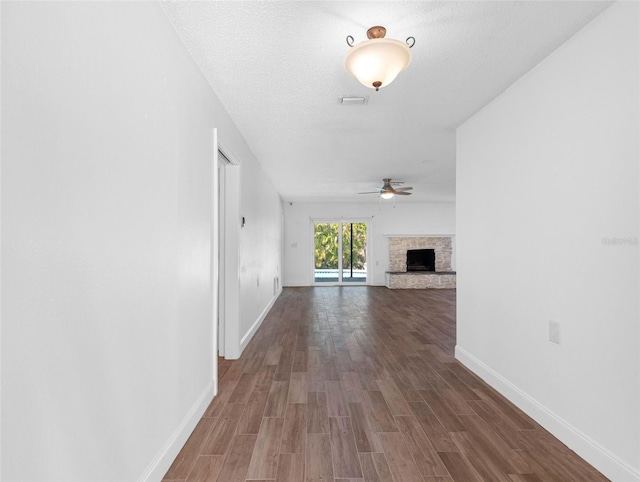 hallway with dark wood-type flooring, baseboards, and a textured ceiling