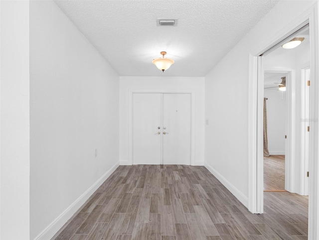 interior space with visible vents, baseboards, a textured ceiling, and wood finished floors