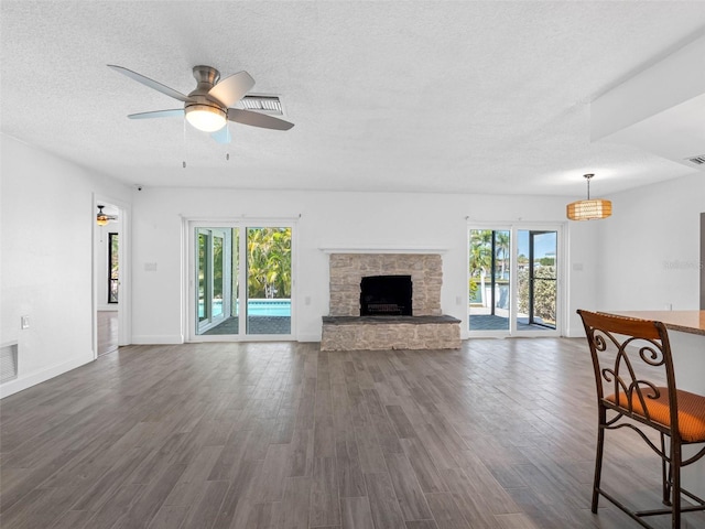 unfurnished living room with visible vents, a ceiling fan, a textured ceiling, a fireplace, and dark wood-style flooring