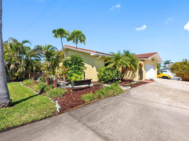 view of front of property with stucco siding, a garage, driveway, and a tiled roof