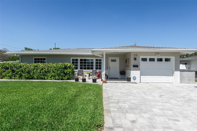 single story home featuring a front yard, decorative driveway, and a garage