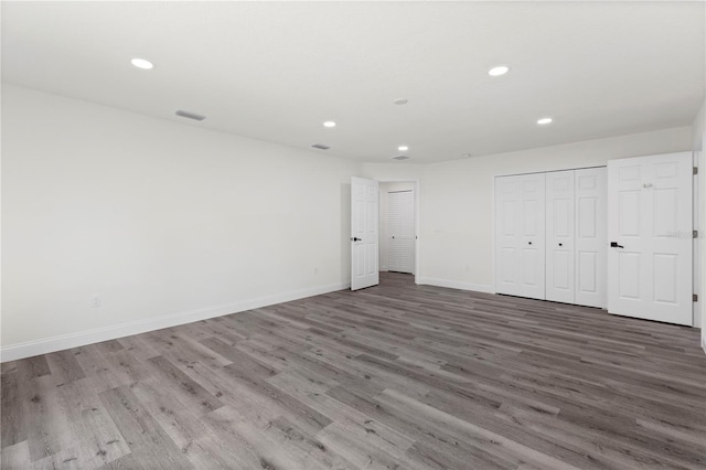 unfurnished bedroom with recessed lighting, baseboards, visible vents, a closet, and wood finished floors