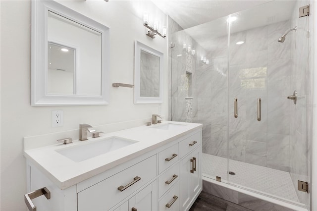full bathroom with a marble finish shower, double vanity, and a sink
