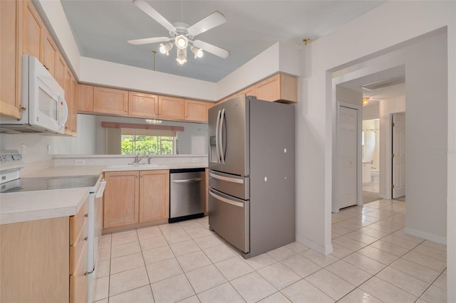 kitchen with light tile patterned floors, light countertops, stainless steel appliances, and light brown cabinets