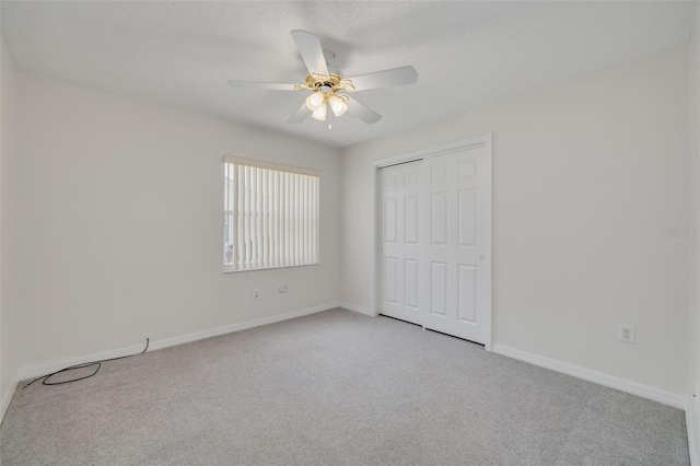 unfurnished bedroom featuring a closet, a ceiling fan, light carpet, and baseboards