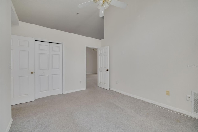 unfurnished bedroom featuring a closet, high vaulted ceiling, ceiling fan, carpet, and baseboards