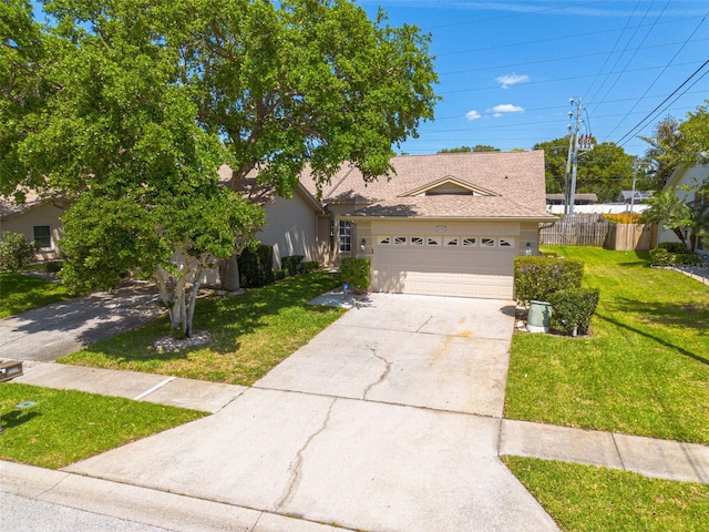 view of front of property featuring fence, a shingled roof, a front lawn, concrete driveway, and an attached garage