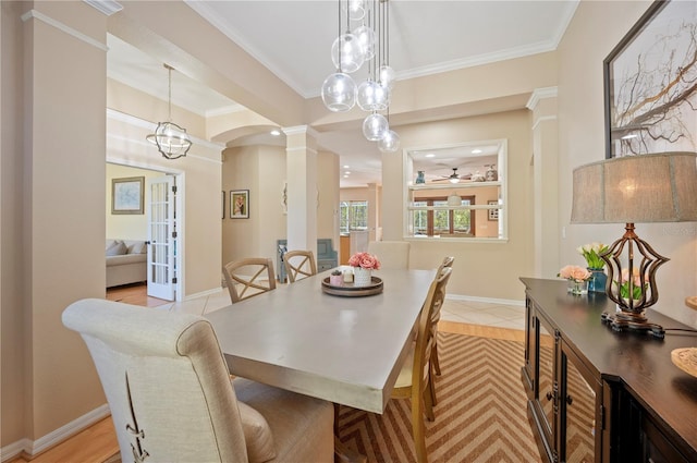 dining space featuring crown molding, ceiling fan, baseboards, french doors, and ornate columns