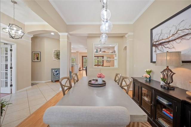 dining space with crown molding, light tile patterned floors, arched walkways, and ornate columns