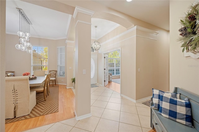 dining room featuring ornamental molding, arched walkways, an inviting chandelier, light tile patterned flooring, and baseboards