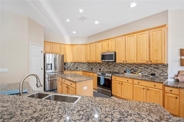 kitchen featuring dark stone countertops, light brown cabinets, a sink, appliances with stainless steel finishes, and backsplash