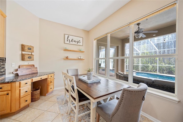 dining area featuring light tile patterned flooring, a ceiling fan, and baseboards