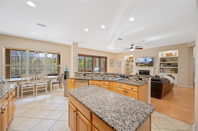 kitchen with a sink, a center island, light tile patterned floors, dishwasher, and ceiling fan