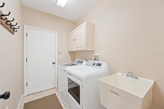 laundry area featuring washer and clothes dryer, cabinet space, light tile patterned flooring, and a sink