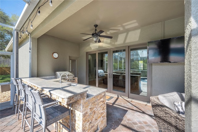 view of patio / terrace with area for grilling, a ceiling fan, outdoor wet bar, a grill, and a lanai