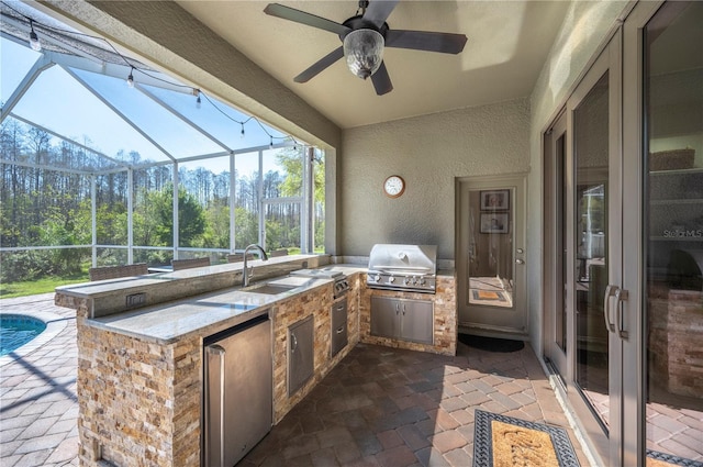 view of patio with a lanai, area for grilling, an outdoor kitchen, and a ceiling fan