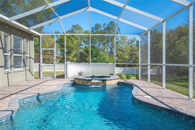 view of pool with a patio area, glass enclosure, a pool with connected hot tub, and fence