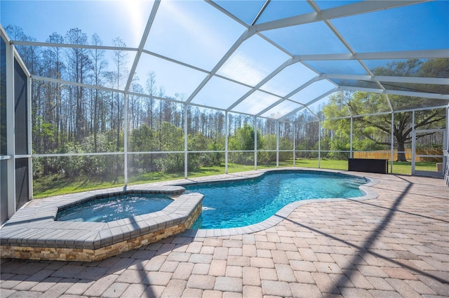 view of swimming pool featuring a patio area, glass enclosure, and a pool with connected hot tub