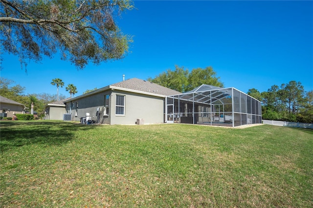 back of property featuring a yard, a lanai, and stucco siding