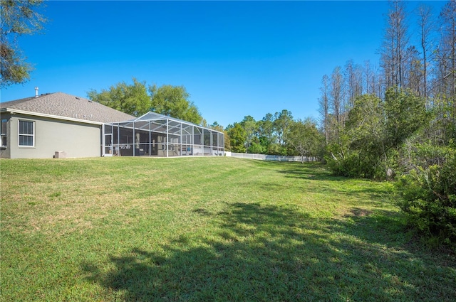 view of yard featuring glass enclosure and fence