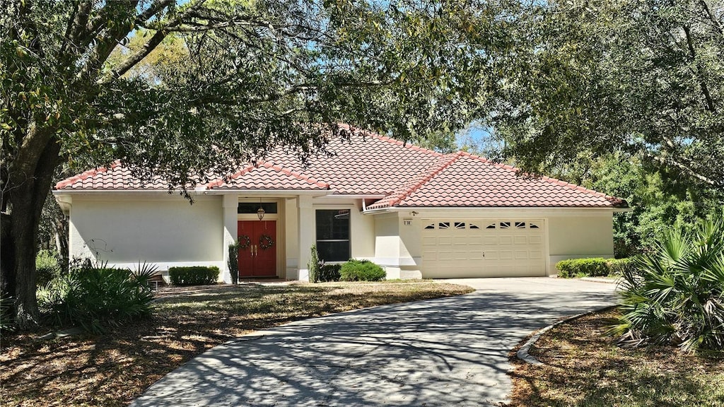 mediterranean / spanish-style house with a tile roof, an attached garage, and stucco siding