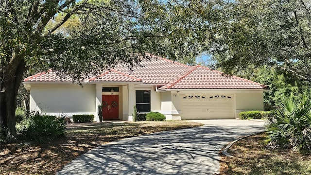 mediterranean / spanish-style house with a tile roof, an attached garage, and stucco siding