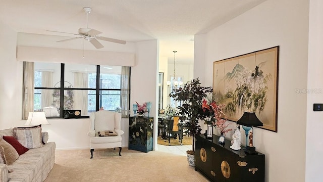 living room featuring ceiling fan with notable chandelier, baseboards, and carpet floors
