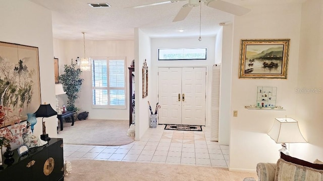 foyer entrance featuring visible vents, light carpet, a ceiling fan, a textured ceiling, and light tile patterned floors