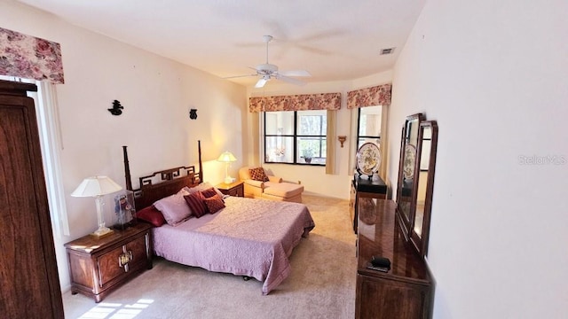 bedroom with visible vents, light colored carpet, and a ceiling fan