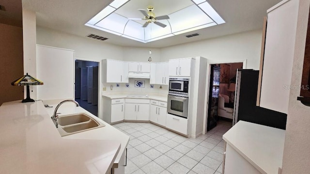kitchen with a ceiling fan, visible vents, a skylight, a sink, and stainless steel oven