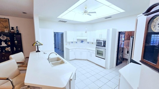kitchen featuring visible vents, stainless steel microwave, oven, a ceiling fan, and a sink