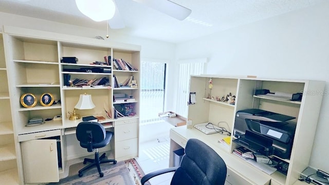 office with built in desk and a ceiling fan