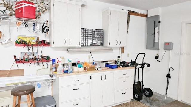 kitchen featuring electric panel, white cabinets, and light countertops