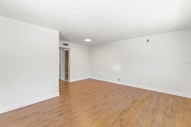 spare room with visible vents, wood finished floors, and baseboards