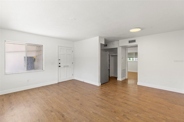 spare room featuring visible vents, baseboards, and wood finished floors