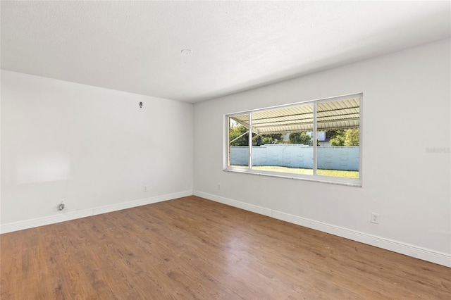 spare room with wood finished floors, baseboards, and a textured ceiling