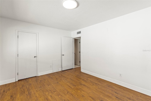 unfurnished bedroom with visible vents, baseboards, and wood finished floors