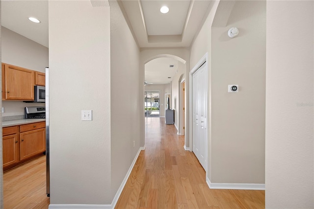 hall with recessed lighting, light wood-type flooring, arched walkways, and baseboards