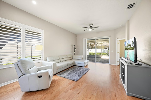 living room featuring visible vents, light wood-style flooring, baseboards, and a ceiling fan