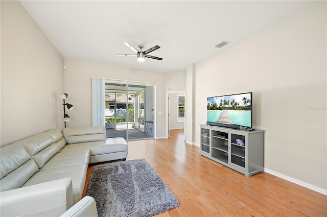 living room with light wood-type flooring, visible vents, baseboards, and a ceiling fan