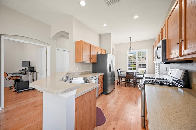 kitchen featuring visible vents, a peninsula, a sink, appliances with stainless steel finishes, and light wood-type flooring