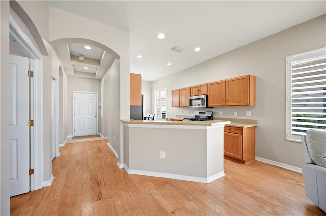 kitchen featuring baseboards, visible vents, arched walkways, appliances with stainless steel finishes, and light wood-type flooring