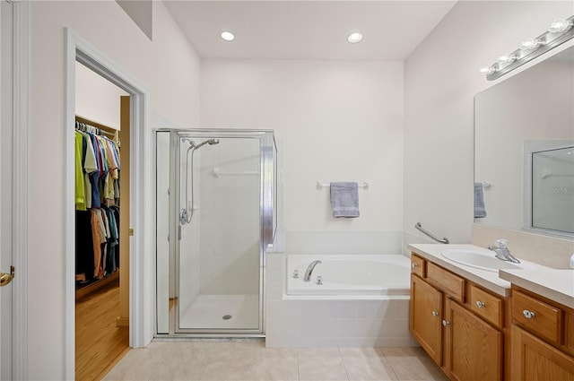 full bathroom with tile patterned floors, a spacious closet, a bath, and a shower stall