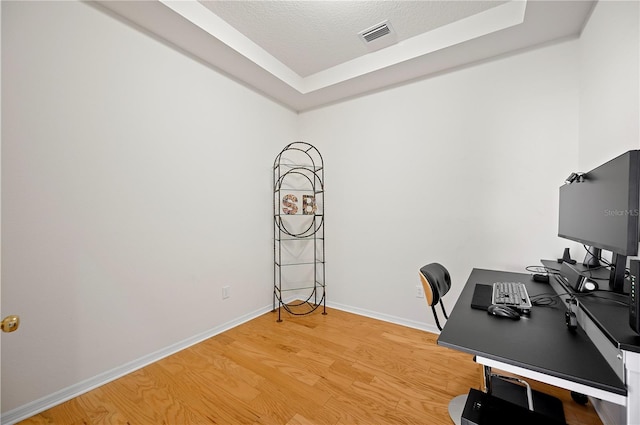 unfurnished office featuring visible vents, light wood-style flooring, a textured ceiling, and baseboards