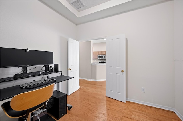 office featuring light wood finished floors, visible vents, and baseboards