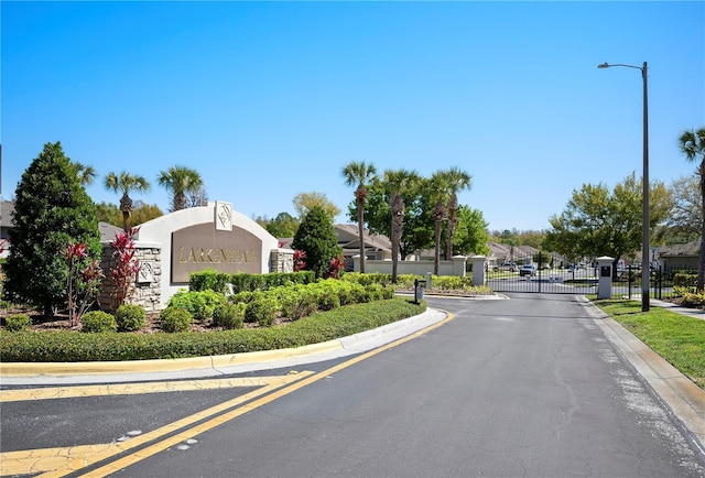 view of street featuring street lights, a gate, curbs, and a gated entry