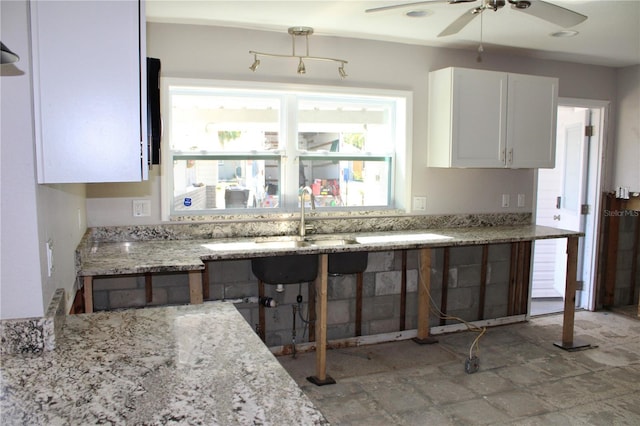 kitchen featuring white cabinetry, a ceiling fan, and light stone countertops