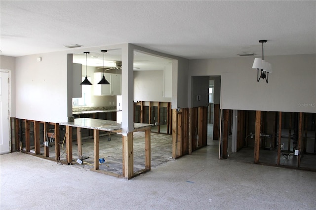 unfurnished room with ceiling fan, light speckled floor, visible vents, and a textured ceiling