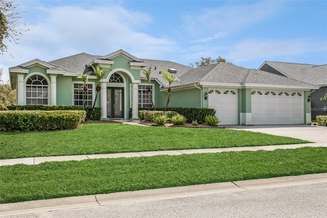 view of front facade featuring stucco siding, a garage, roof with shingles, and a front lawn